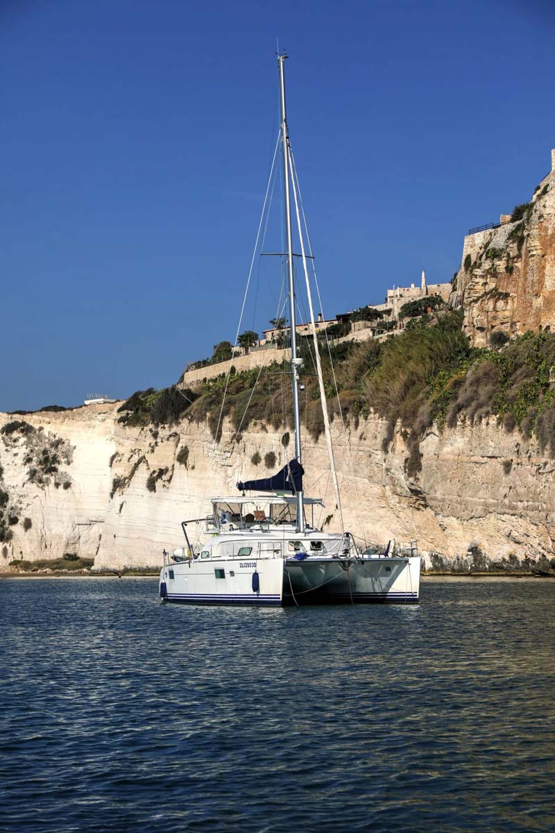 White yacht and sailboats on blue sea