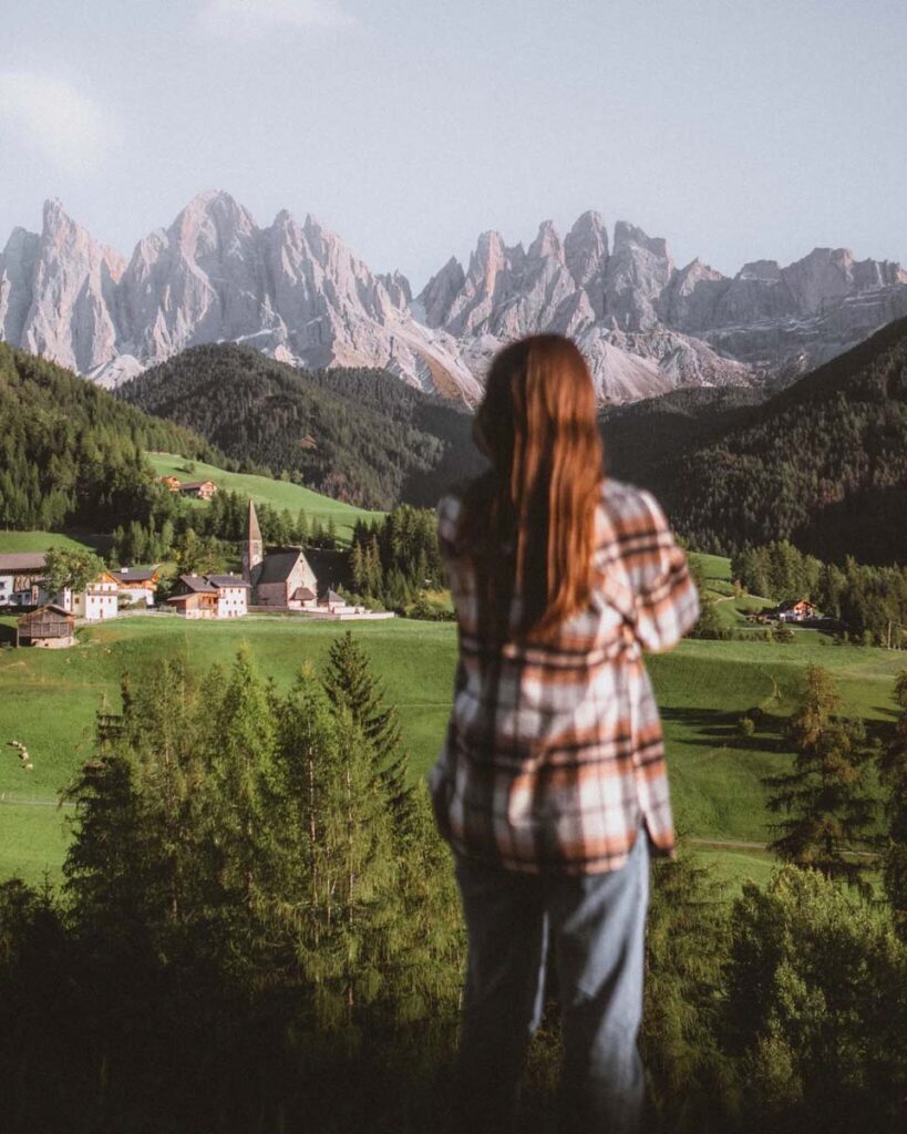 Red hair woman looking to a small village in green hills