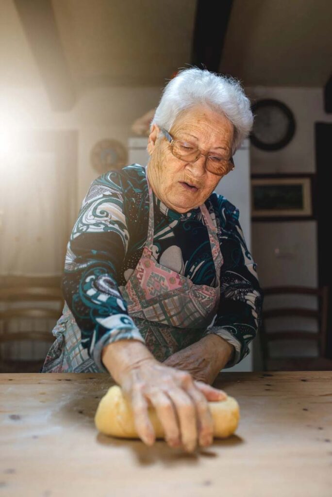 Old woman cooking in her kitchen traditional recipes of Italian homemade pasta