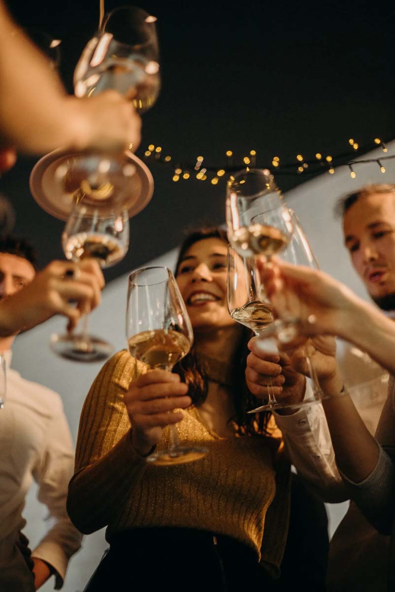 Smiling young people drinking wine at night